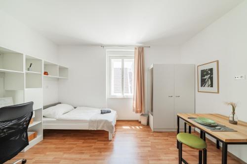 维也纳新城Central City Suits的一间卧室配有一张床、一张桌子和一张桌子