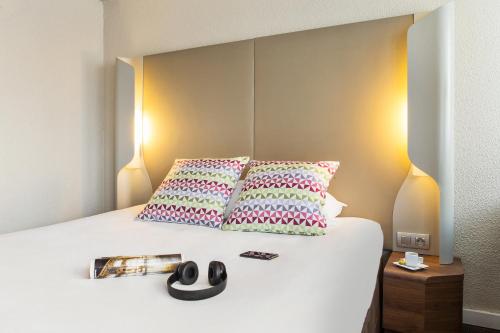 德勒德勒钟楼酒店的一间卧室配有一张带两个枕头和杂志的床