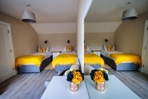 基拉尼9 Parklands Holiday home的一间设有三张床、黄色枕头和鲜花的客房