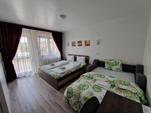 图尔达Pensiunea Bella Vista的客房设有两张床、一张桌子和一扇窗户。
