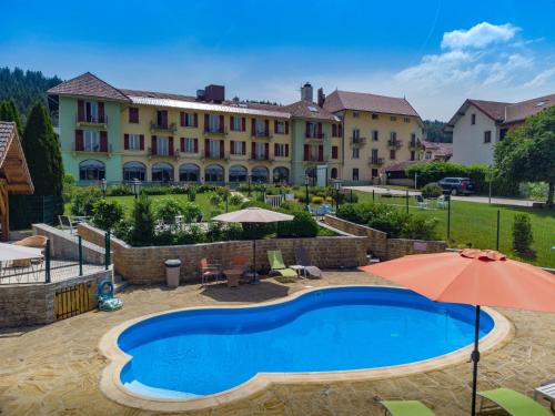 马尔比伊松勒拉克餐厅酒店的一座带游泳池的度假村,位于一座建筑前