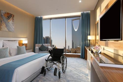 利雅德Cantonal Hotel by Warwick的卧室在窗户前配有带轮椅的床
