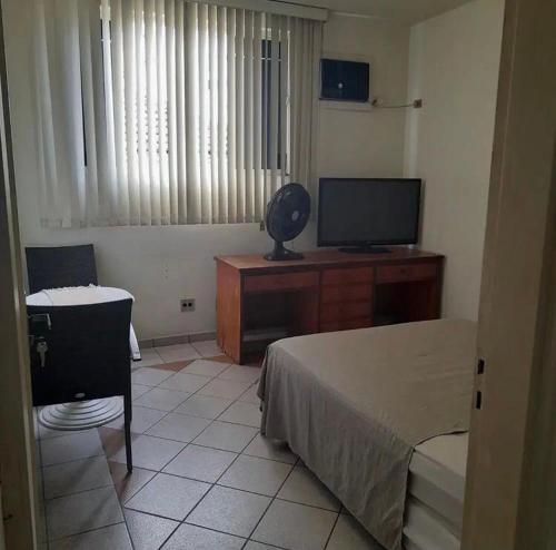 桑托斯Quattrô suítes Santos的一间卧室配有一张床和一张书桌及电视