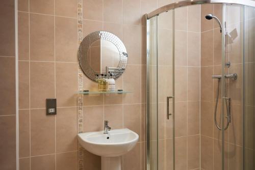 希普利Victoria Mills Apartment Shipley的浴室配有盥洗盆和带镜子的淋浴