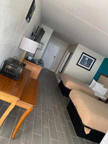 默特尔比奇Summer Wind Ocean Front Hotel的一间酒店客房,设有一张床铺、一张桌子和一张床,