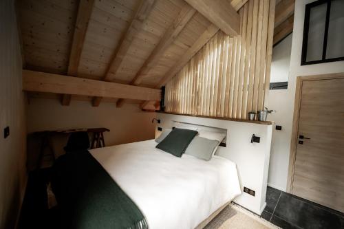 普雷芒翁La Loge de la Dolarde - Chambre Ouest的卧室设有白色的床和木制天花板。