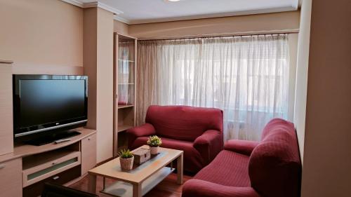 奥伦塞Leiras Pulpeiro con Garaje的客厅配有2把红色椅子和平面电视