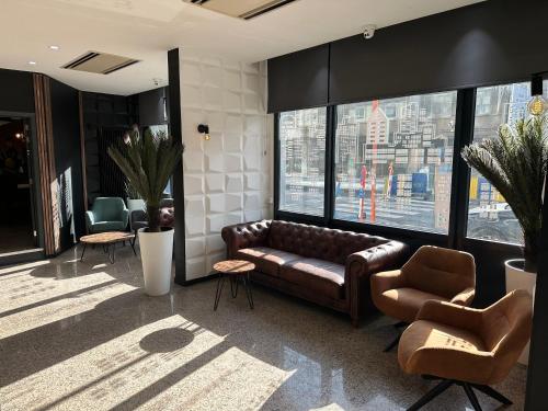 布鲁塞尔Hotel EUROPACITY的客厅配有真皮沙发和两把椅子