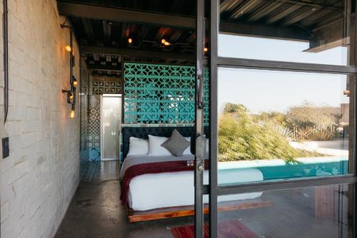 瓜达鲁佩镇Hotel Los Amantes Valle de Guadalupe的一间卧室设有一张床和一个游泳池
