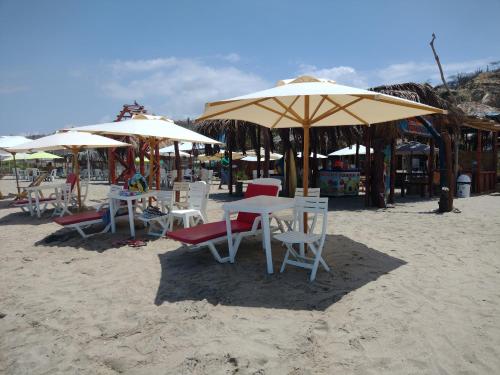 通贝斯La palmera zorritos的海滩上一组桌椅和遮阳伞