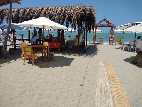 通贝斯La palmera zorritos的沙滩上配有桌椅和遮阳伞的海滩