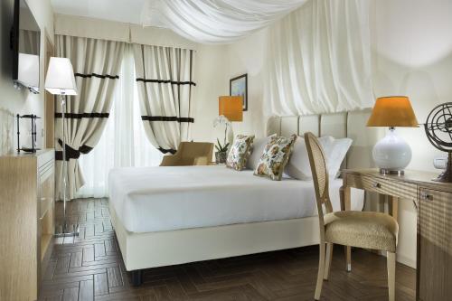 里米尼厄尔巴沃格里奥酒店的卧室配有白色的床、书桌和椅子