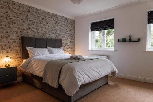 艾尔斯伯里Comfortable 4-Bedroom Home in Aylesbury Ideal for Contractors Professionals or Larger Families的一间卧室设有一张带砖墙的大床