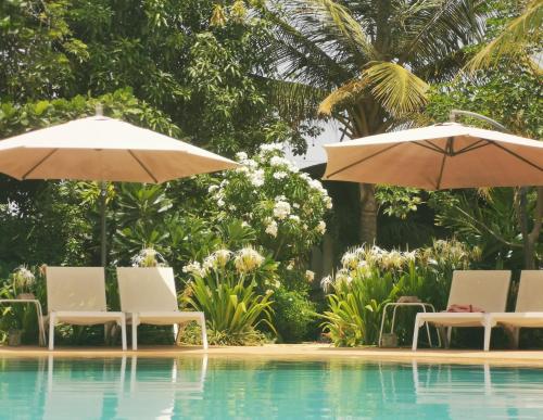 恩加帕鲁La Maison Vanille的游泳池旁的两把遮阳伞和椅子