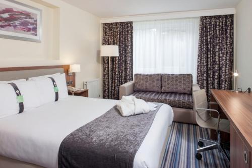 特伦特河畔斯托克Holiday Inn Stoke on Trent M6 Jct15, an IHG Hotel的配有一张床和一张书桌的酒店客房