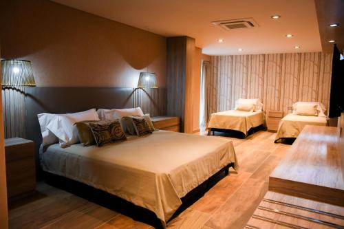 特尔马斯德里奥翁多Hotel Cálido Termal的酒店客房设有两张床和两盏灯。