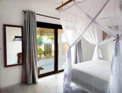 托弗海滩Casa do Índico的卧室配有白色的天蓬床和窗户。