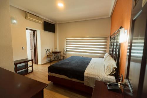 瓜达拉哈拉Hotel Alcazar - Guadalajara Centro Historico的卧室配有一张床和一张桌子及椅子
