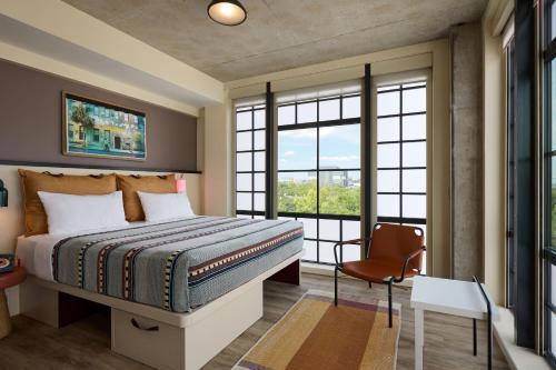 查尔斯顿Moxy Charleston Downtown的一间卧室配有一张床、一把椅子和窗户。