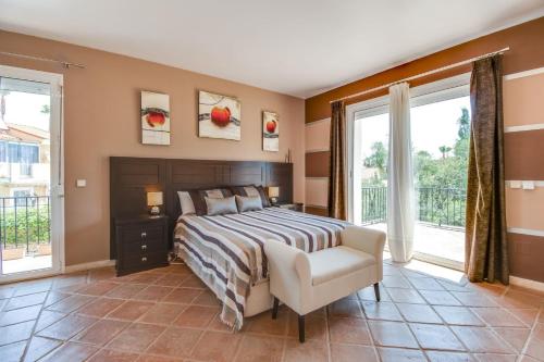 马尼尔瓦Villa Duquesa的一间卧室配有一张床、一把椅子和窗户。