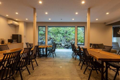 上田市Bessho Onsen Midoriya的餐厅设有木桌、椅子和大窗户。