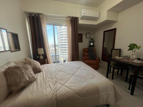 达沃市Inspiria Condominium Tower, beside Abreeza Ayala Mall, Davao City的卧室配有白色的床、书桌和窗户。