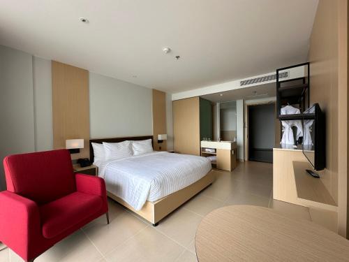 Miếu ÔngThe Arena Cam Ranh Resort all Luxury Service的一间卧室配有一张床和一张红色椅子