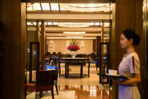 三亚金茂三亚亚龙湾丽思卡尔顿酒店的一位女士在带桌子的饭厅里散步