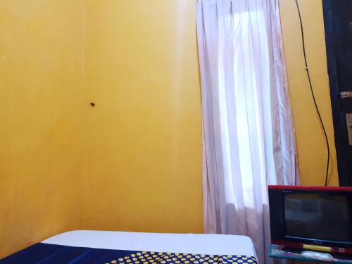 外南梦SPOT ON 92857 Kos Haji Jakfar Syariah的一间卧室配有床、电视和窗帘