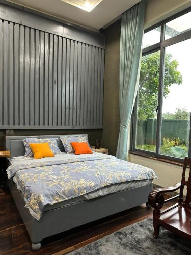 邦美蜀Ylang Farmstay的一间卧室配有带橙色枕头的床和窗户。