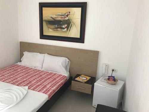 内瓦Hotel Madrid Deluxe Neiva的卧室配有一张床,墙上挂着一幅画