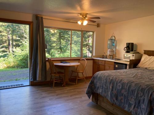 海恩斯罗德之家海滩山林小屋的一间卧室配有一张床铺和一张桌子,还设有一间厨房