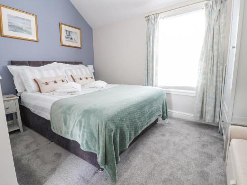 康威Millgate Cottage的一间卧室配有一张带绿毯的床和窗户。