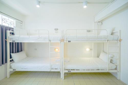 曼谷PICCOLO SUKHUMVIT HOSTEL的白色墙壁的客房内设有两张双层床。