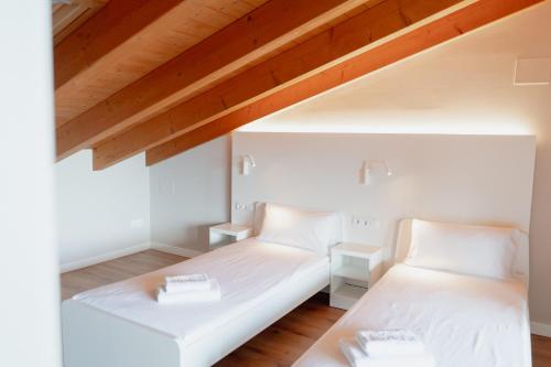 波夫拉德塞古尔LA CASA del TOMÀS的配有白色墙壁和木制天花板的客房内的两张床