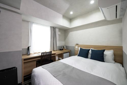 秋田Hotel KAN-RAKU Akita Kawabata的一间卧室配有一张床、一张书桌和一个窗户。
