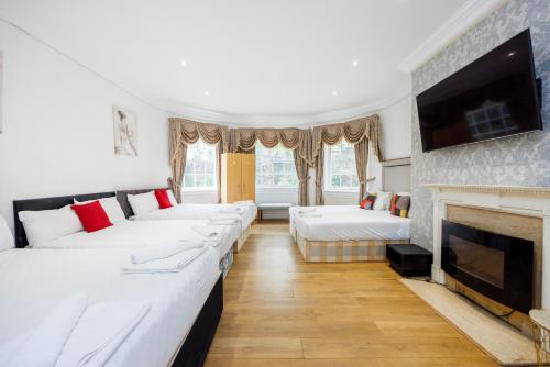 伦敦Larger Groups Canary Wharf Apartment with Large Garden & Parking的客房设有四张床和壁炉。