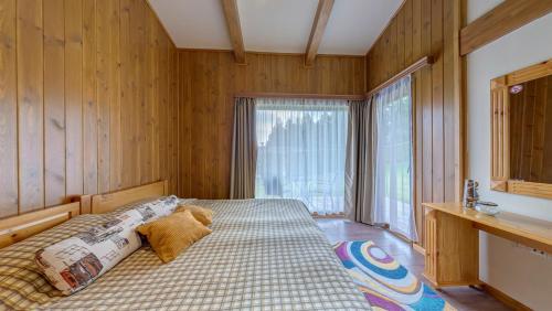 拉兹洛格Boutique Holiday Pirin Golf的一间卧室配有一张带木墙和窗户的床。