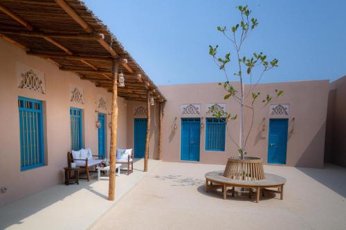 豪尔费坎Nozol Al Rayaheen By Sharjah Collection的一个带蓝色门的庭院和一张桌子及树