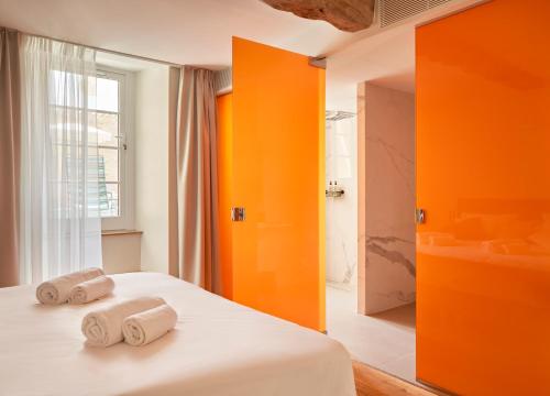 蒙帕齐耶hideauts hotels Le Chevalier bleu的一间卧室拥有橙色的墙壁,床上配有2条毛巾