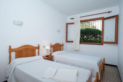 穆罗海滩Miloca 2的白色客房的两张床,设有窗户