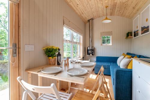 巴拉特Enchanting Tiny House with wood burner and hot tub in Cairngorms的用餐室以及带桌椅的起居室。