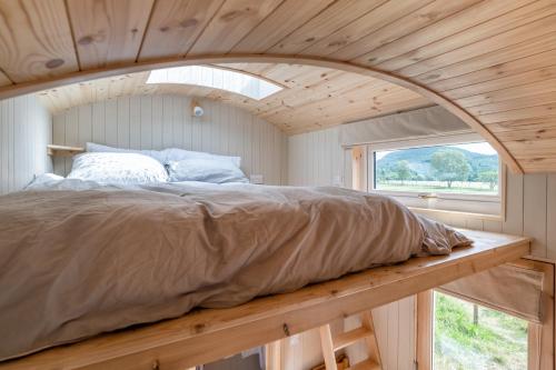 巴拉特Enchanting Tiny House with wood burner and hot tub in Cairngorms的一个小房间的一个床位,设有窗户