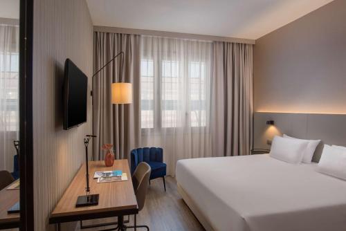 的里雅斯特NH特里斯特酒店的酒店客房带一张床、一张桌子、一张床和窗户。