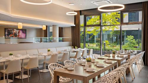蒙海姆Hey Lou Hotel Monheim am Rhein的用餐室设有桌椅和窗户。