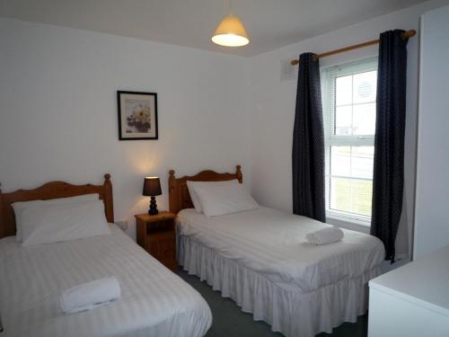 巴利巴宁Ballybunion Holiday Homes No 21的一间卧室设有两张床和窗户。