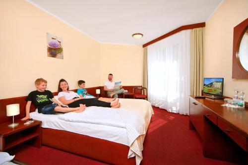 哈拉霍夫斯沃诺斯特健康酒店的三人坐在酒店房间的床上