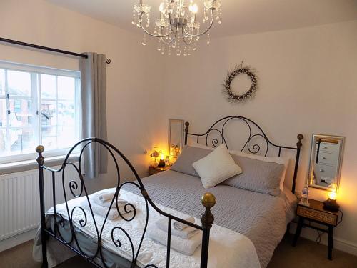 埃姆斯伯里Double Award Winning, Stunning 1700's Grd 2 listed cottage near Stonehenge - Elegantly Refurbished Throughout的一间卧室配有一张床和一个吊灯