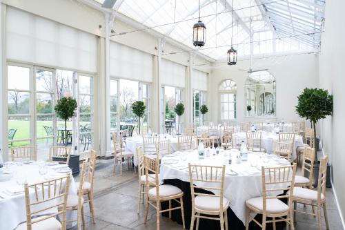 Buxted精选巴克斯特德公园乡村别墅酒店的配有白色桌椅和窗户的客房