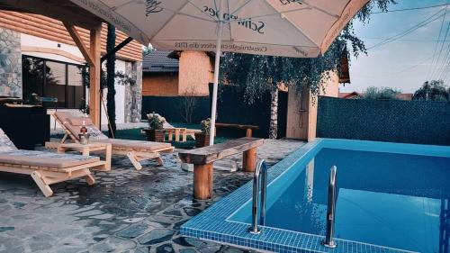 科马尔尼克CASA DE VACANTA CLARA MARIA的一个带游泳池、遮阳伞和桌子的庭院